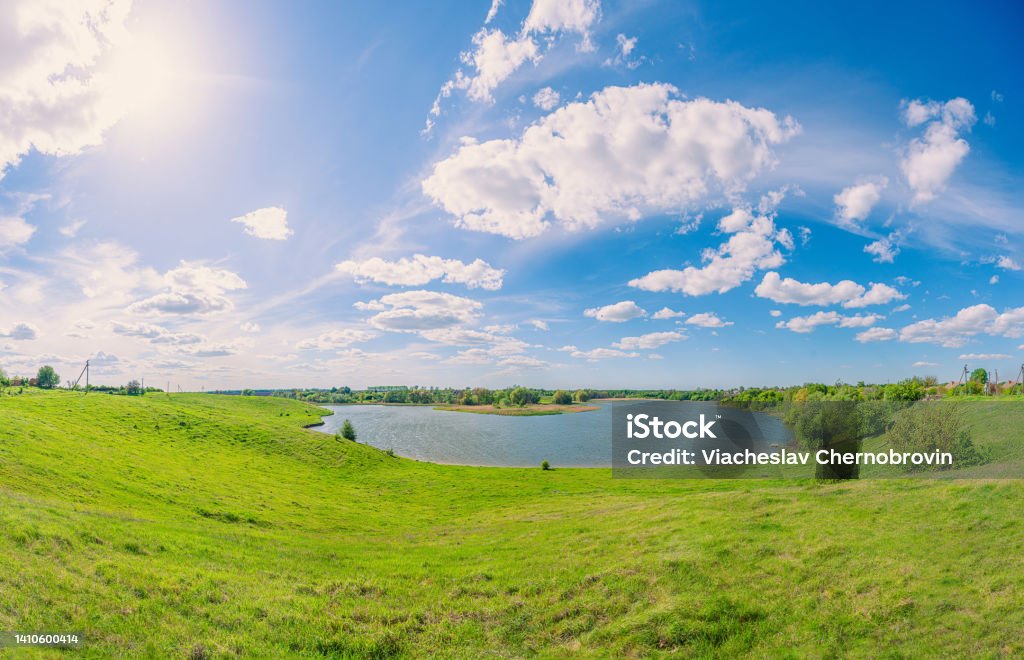 Green field and blue pond in the village Vchorayshe, Zhytomyr Region, Ukraine Agricultural Equipment Stock Photo