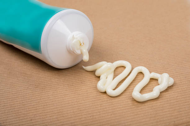 istock Pharmaceutical medicine or healing topical application ointment concept with plastic tube pushing white cream 1410603450