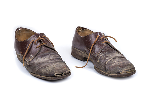 A pair of old, well-used running shoes, all logos and brand markings removed, shot on studio white