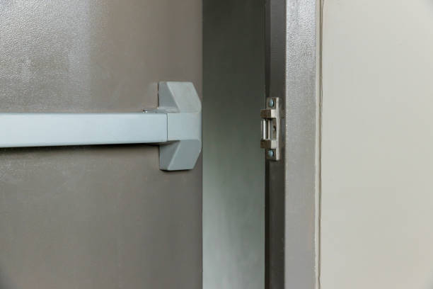istock Emergency fire exit door. Closed up latch and rusty door handle of emergency exit. Push bar and rail for panic exit. Open one way door. steel of handle for the white door fire exit 1410604261