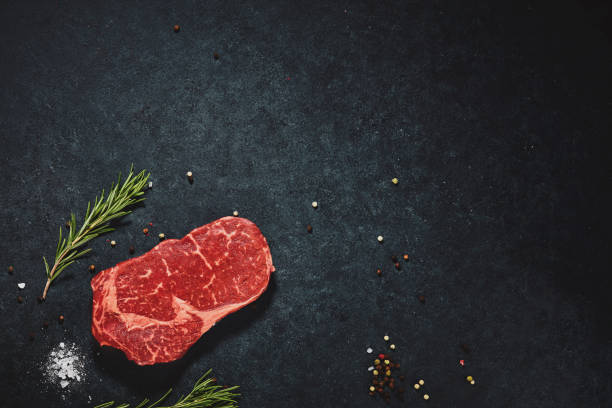 istock Top view raw chop meat steak with salt and pepper on black textured copy space background. Flat lay food photography 1410605447
