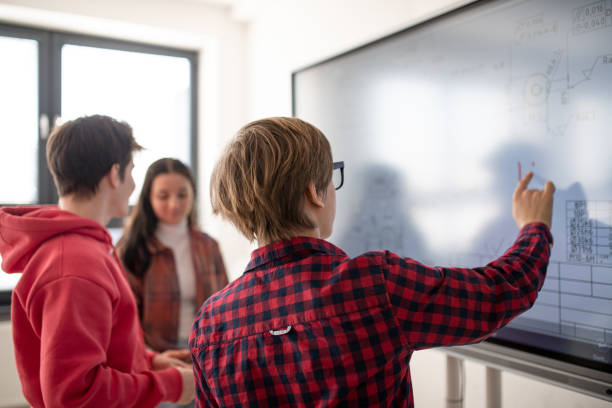 istock College student explaining some ideas on a touch TV in classroom. 1410609464