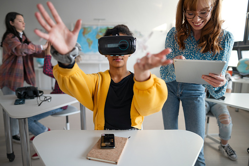 Teenage students wearing virtual reality goggles at school in a computer science class