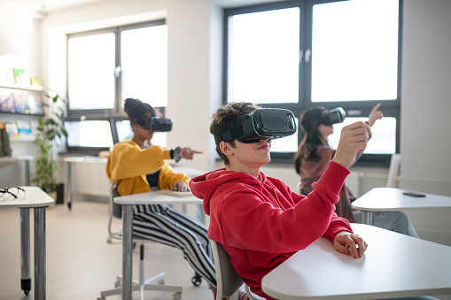 Teenage students wearing virtual reality goggles at school in a computer science class