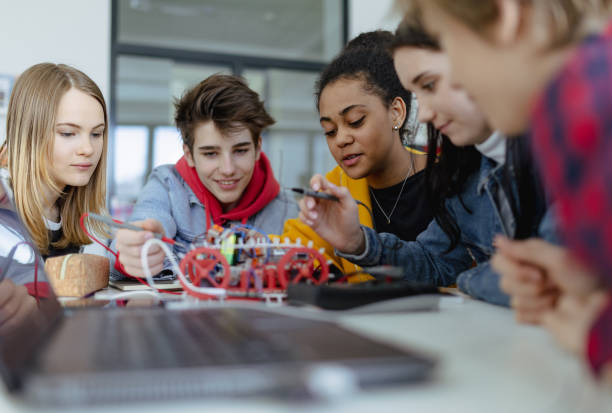 ロボット教室で電気玩具やロボットを組み立て、プログラミングする高校生のグループ - high school high school student classroom group of people ストックフォトと画像