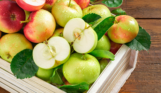 Harvest fresh red and green apples in wooden box on wooden table close up top view with copy space