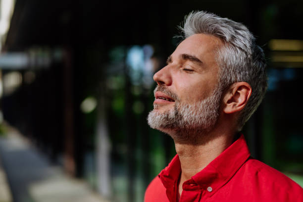 istock Cheerful mature businessman keeping eyes closed and taking a deep breath while standing outside during a break from work. 1410615018