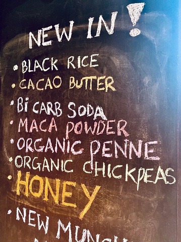 Vertical chalk board with list of foods available in colored chalk outside health food store in rural Bangalow Australia