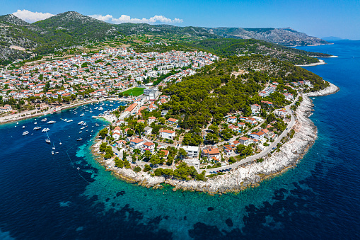 Magical Hvar old town, part of Split-Dalmatia County in Croatia, seen from a drone perspective during a summer season with many boats and yachts anchored in its port.