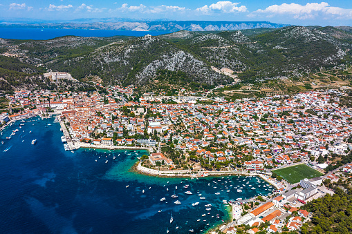 Hvar old town and port on the island of Hvar, part of Split-Dalmatia County, Croatia, seen from a drone point of view during a summer season with many boats and yachts.