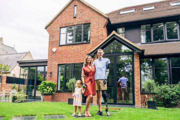 Portrait of happy family moving into their new luxury home, house or property in summer. Parent, grandparents and girl standing on the grass, lawn, backyard or garden with a smile   together