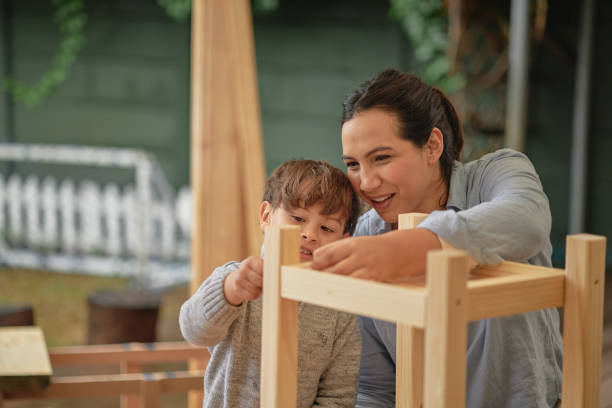 Mother teaching son about DIY while doing project at home. Little boy child helping carpenter mom to build a wooden chair. Young kid and parent assembling furniture and enjoying a craft activity