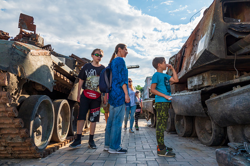 2022-07-21 Kyiv, Ukraine. Ukrainian family with children look at the destroyed russian warfare on the exibition at Mikhailivskiy square in the center of Kyiv