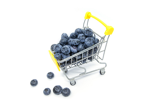 small shopping cart full of fresh blueberry isolated. selective focus