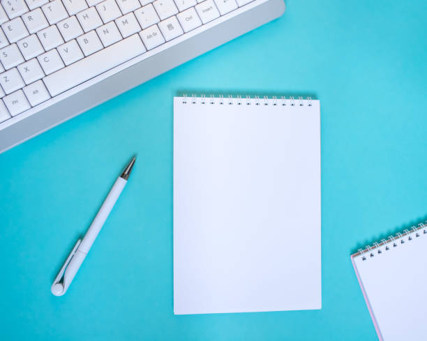 istock An empty notepad with a pen is on a blue background with a laptop and supplies. Top view with copy space, flat lay. 1410629611