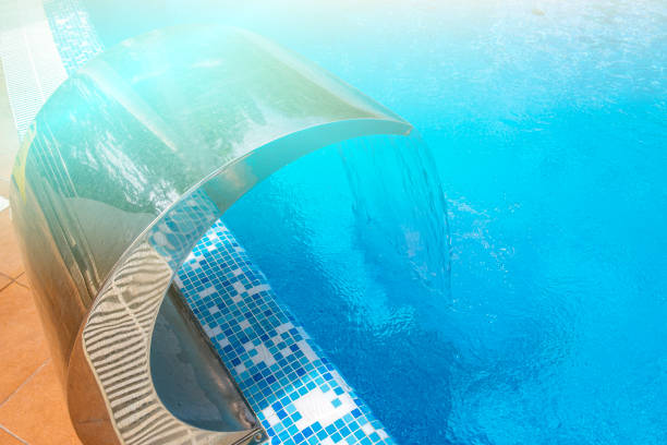 istock Pool side. Empty outdoors swimming pool and waterfall jet on summer sunny day. Seaside vacation and hotel resort concept. Reflection in blue clean sea water pool 1410634413