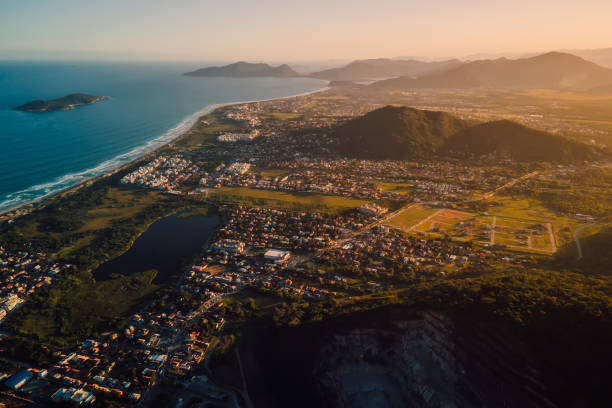 Ocean coastline and town with sunset lights in Campeche, Florianopolis Ocean coastline and town with sunset lights in Campeche, Florianopolis florianópolis stock pictures, royalty-free photos & images