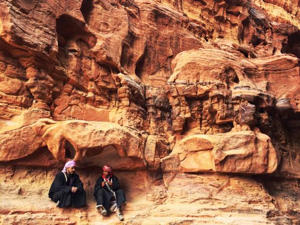 Wadi Rum, Jordan - December 30, 2018: Two male Bedouins escaping the midday heat and taking a break in a canyon in Wadi Rum desert in the south of Jordan.
