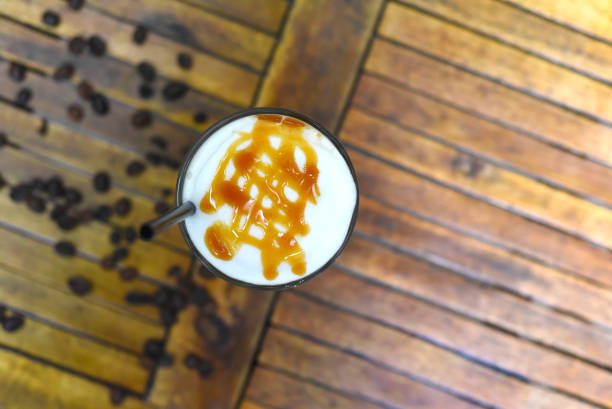 Ice caramel latte with coffee beans isolated on wooden table