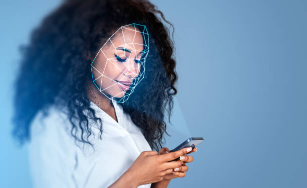 Black businesswoman with smartphone, using facial scanner smiling stock photo