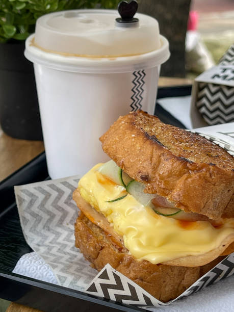 Egg and ham sandwich and coffee in disposable cup