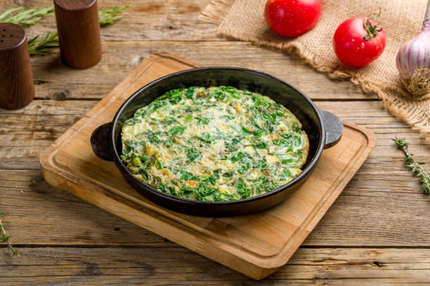 omelet with spinach, greenery and cheese on old wooden table omelet with spinach, greenery and cheese on old wooden table frittata stock pictures, royalty-free photos & images