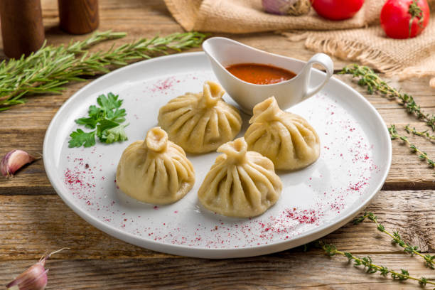istock Khinkali with lamb and tomato sauce on white plate on old wooden table 1410643529