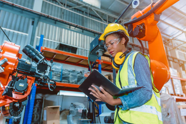 ingegnere donna intelligente che lavora programmando saldatrice robotizzata. la ragazza adolescente nera lavora in anticipo fabbrica moderna. - manufacturing foto e immagini stock