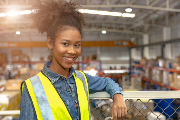 portrait jeune adolescent africain fille noire adolescente travail dans un grand entrepôt usine stock heureux souriant. - premier emploi photos et images de collection