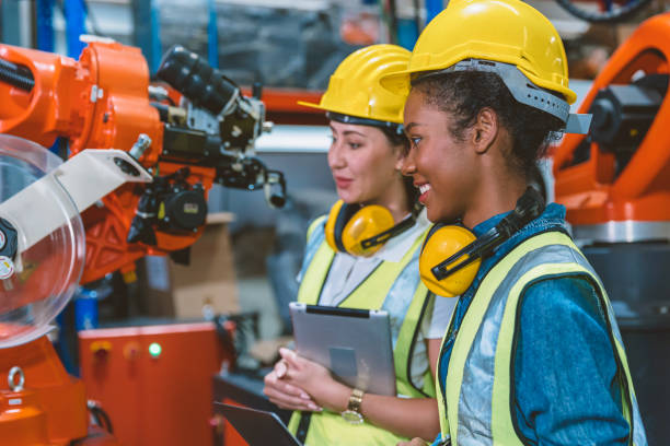 Women engineer worker working team helping together at work in modern advance machine factory. stock photo