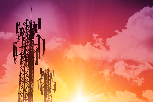 5G Communication tower or 4G network telephone cellsite silhouette on sunny colorful sky background.