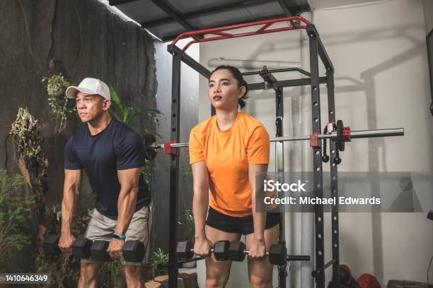 A Man And Woman Simultaneously Doing A Set Of Romanian Deadlifts Couple Working Out At A Home Gym Stock Photo - Download Image Now