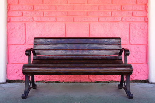 Wooden bench near Pink Brick Stone Wall Background