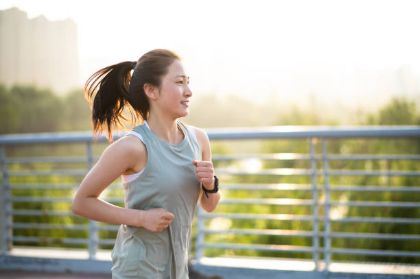 asiatische junge frau, die morgens auf der stadtstraße läuft - running jogging women marathon stock-fotos und bilder