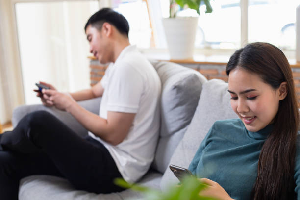 istock Asian couples are sitting on the phone indifferently to each other. 1410654846