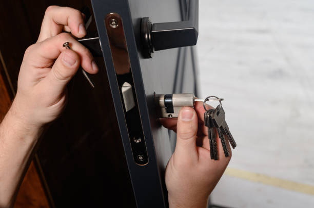 o mestre instala o núcleo para a fechadura da porta, trabalho de instalação com a porta. - metal door measuring work tool - fotografias e filmes do acervo