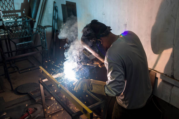 istock Welding the corner joint of a steel bench. Using a level bar to check balance. Creating custom furniture at a workshop or factory. 1410657735