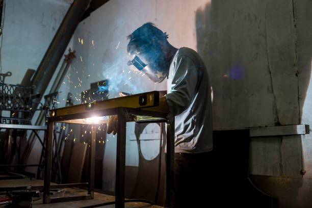 istock Welding the corner joint of a steel bench. Using a level bar to check balance. Creating custom furniture at a workshop or factory. 1410657737