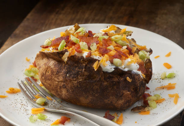 Loaded Baked Potato Loaded Baked Potato with Bacon, Sour Cream, Cheddar Cheese and Scallions baked potato sour cream stock pictures, royalty-free photos & images
