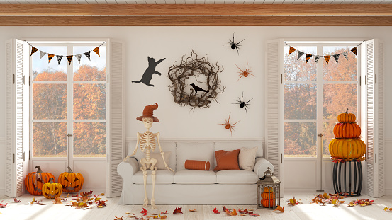 Halloween interior design, living room with skeleton sitting on the sofa in white tones. Panoramic windows on autumnal landscape. Party decorations, modern scandinavian style