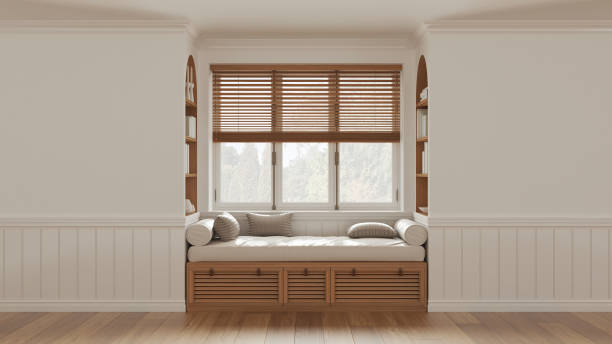Classic window with siting bench and pillows. Wooden venetian blinds, bookshelf and decors. White walls with copy space for text. Modern interior design stock photo