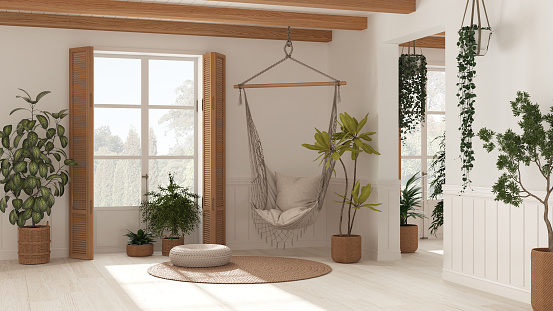 Farmhouse living room in Boho style, white tones, potted plants and lace hanging chair. Window with wooden shutters and parquet. Bohemian interior design, boho style