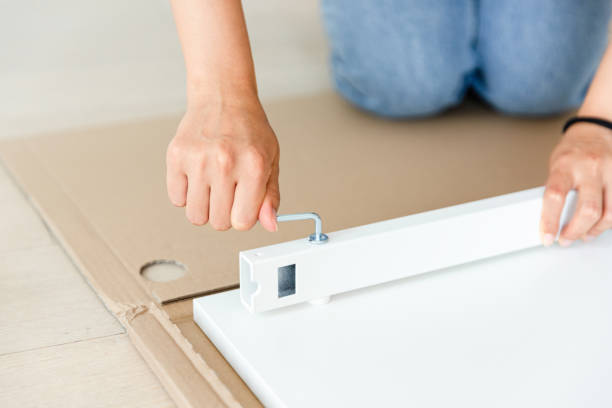 白い厚板にねじ込む女性の手。16進キーを使用する。新しい家具を組み立てる。クローズ アップ。 - screwdriver screw tighten fastener ストックフォトと画像