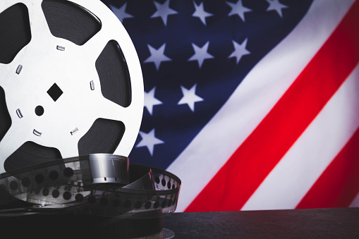 American cinema. Cinematography in the USA. Old film reel on the background of the flag of America.