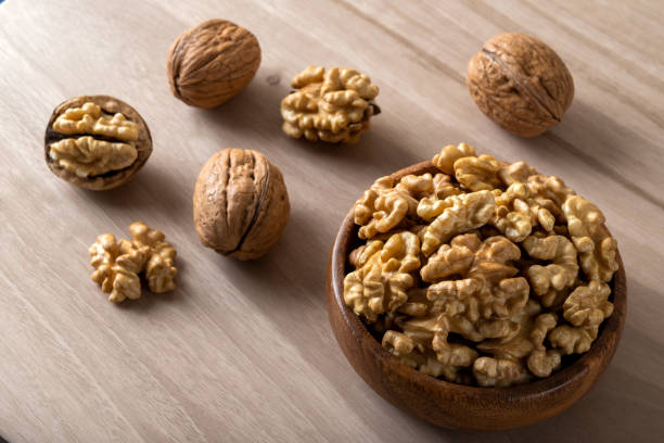 istock Peeled walnuts and whole walnuts on wooden background 1410669863