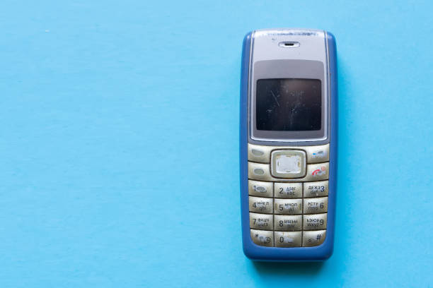 Old blue button mobile phone on blue background stock photo