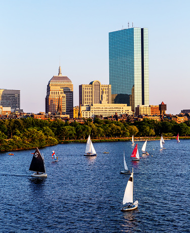 Boston, Massachusetts, USA - July 22, 2022: Sunset on the Boston Back Bay skyline including the John Hancock Tower and the Charles River with sailboats.