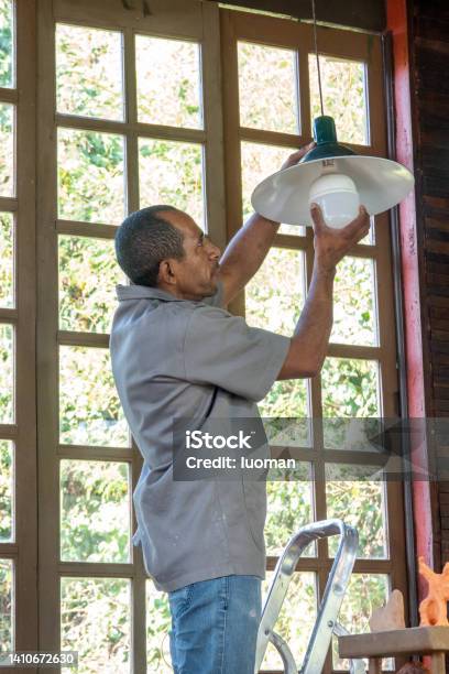 Electrician Removes Light Bulb From A Light Fixture Stock Photo - Download Image Now