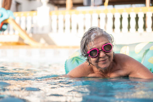 happy senior woman learns to swim and relaxes on a float in summer stock photo