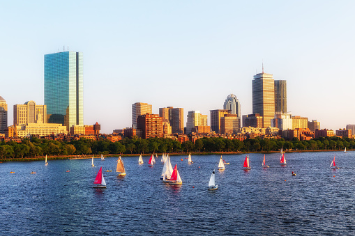 Sunset on the Boston Back Bay skyline iand the Charles River with sailboats.